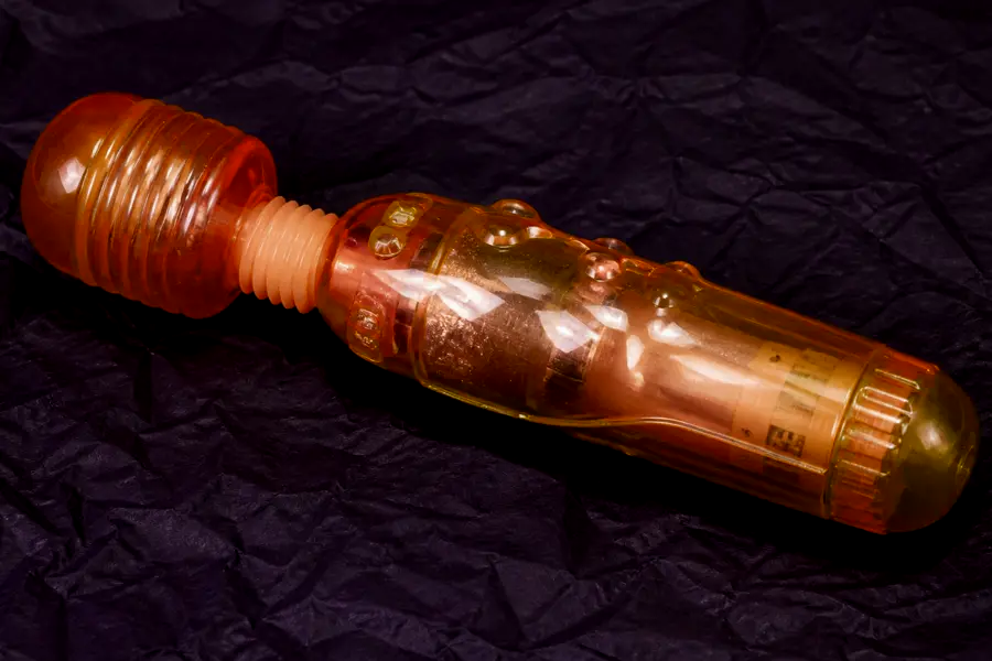 Glossy translucent pink jelly wand on crumpled dark paper. Warning example, not a product to buy.